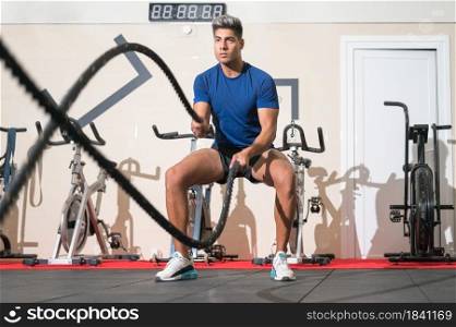 Man working out with rope in functional training fitness gym. High quality photo.. Man working out with rope in functional training fitness gym.
