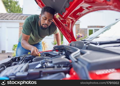 Man Working Under Hood Checking Car Engine Oil Level On Dipstick