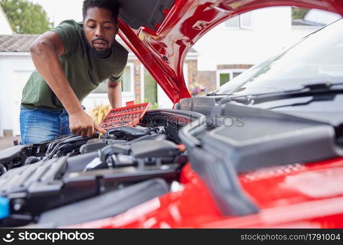 Man Working Under Hood Of Car Fixing Engine With Wrench