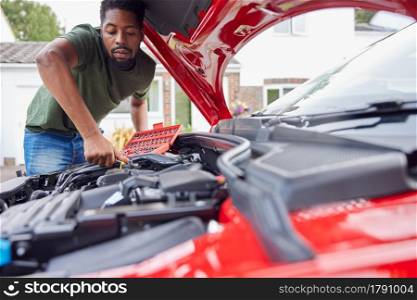 Man Working Under Hood Of Car Fixing Engine With Wrench