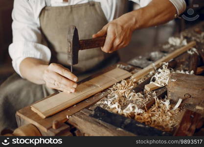 Man working with a wood. Carpenter in a white shirt