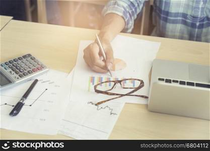 man working with calculator, business document and laptop computer notebook, vintage tone