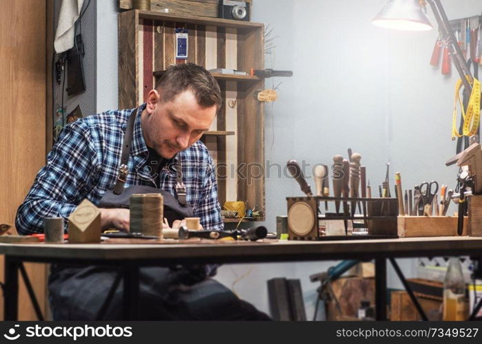 Man working with leather textile at a workshop. Concept of handmade craft production of leather goods.. Concept of handmade craft production of leather goods.