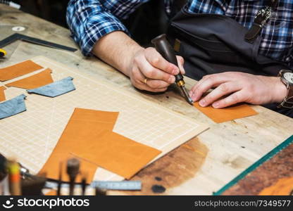 Man working with leather textile at a workshop. Concept of handmade craft production of leather goods.. Concept of handmade craft production of leather goods.