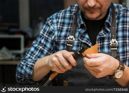 Man working with leather textile at a workshop.. Concept of handmade craft production of leather goods.