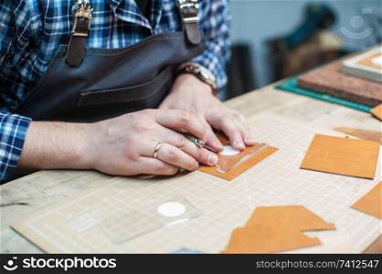 Man working with leather textile at a workshop. Concept of handmade craft production of leather goods.. Concept of handmade craft production of leather goods.