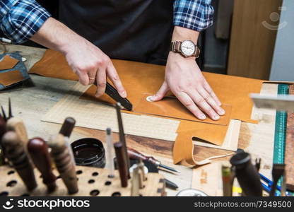 Man working with leather textile at a workshop. Craftman cutting leather. Concept of handmade craft production of leather goods.. Concept of handmade craft production of leather goods.