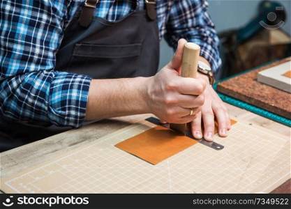 Man working with leather textile at a workshop. Craftman cutting leather. Concept of handmade craft production of leather goods.. Concept of handmade craft production of leather goods.