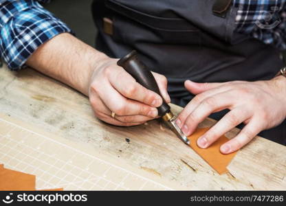 Man working with leather textile at a workshop. Craftman cutting leather. Concept of handmade craft production of leather goods.. Concept of handmade craft production of leather goods.