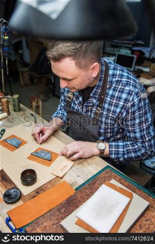 Man working with leather textile at a workshop. Male portrait. Concept of handmade craft production of leather goods.. Concept of handmade craft production of leather goods.