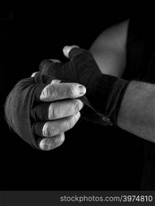 man wraps his hands in black textile bandage for sports, black and white photo