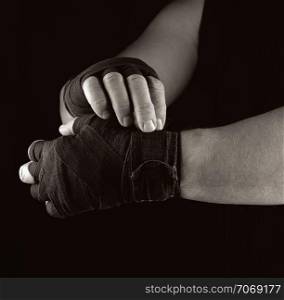 man wraps his hands in black textile bandage for sports, sepia