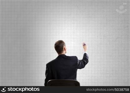 Man write on wall. Rear view of businessman in chair writing on wall