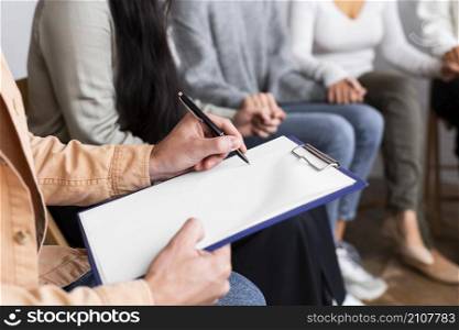 man writing clipboard group therapy session