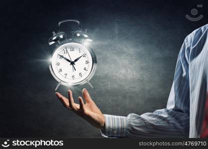 Manage your time. Close up image of human hand holding alarm clock