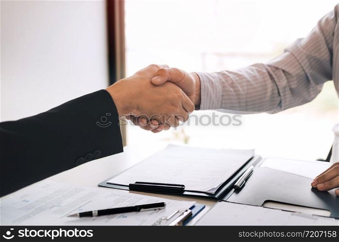 Manager and employee interview concept with handshake after talking about contract signing.