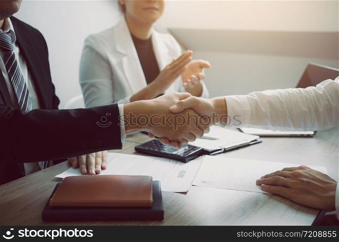 Manager and employee interview concept with handshake after talking about contract signing.