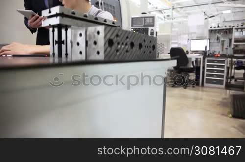 Manager and worker working with documents at plant near CNC machines