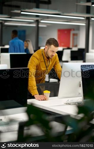 Manager at his workplace in IT office. Professional teamwork and planning, group brainstorming and corporate work, modern company interior on background. Manager at his workplace in IT office