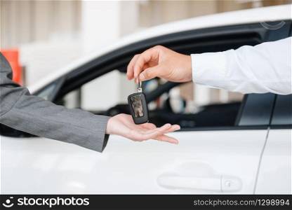 Manager gives to woman the key to the new car in showroom. Female customer buying vehicle in dealership, automobile sale
