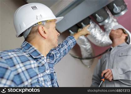 manager giving orders to coworkers fixing air conditioning