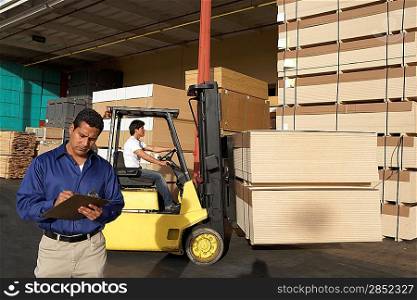 Manager Holding Clipboard on Loading Dock of Lumber Warehouse