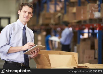 Manager In Warehouse Checking Boxes Using Digital Tablet