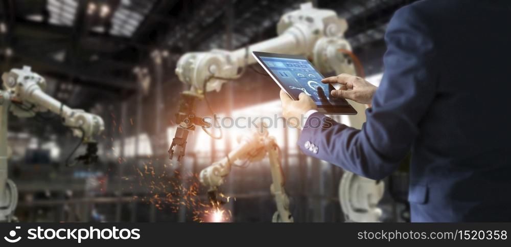 Manager industrial engineer using tablet check and control automation robot arms machine in intelligent factory industrial on real time monitoring system software. Welding roboticts and digital manufacturing operation. Industry 4.0 concept