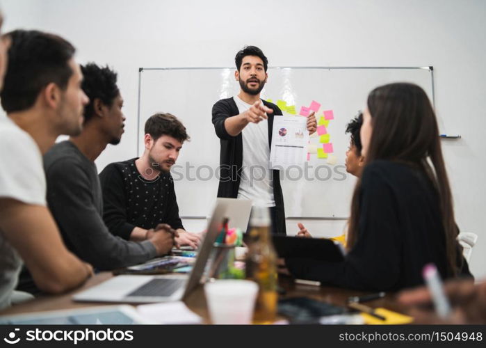 Manager leading a brainstorming meeting with a group of creative designers in the office. Leader and business concept