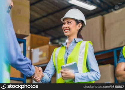 Manager of warehouse worker hand shake with assistant manager woman in local warehouse or factory, Asian and white caucasian people,Partner and colleague working together in success achievement concept