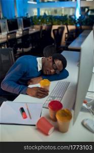 Manager sleeping at the table, night office lifestyle. Male person at laptop, dark interior on background, modern workplace. Manager sleeping at table, night office lifestyle