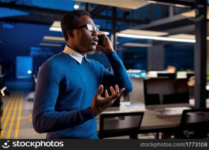 Manager talking by phone, office lifestyle. Male person at the table, dark business center interior on background, modern workplace. Manager talking by phone, office lifestyle