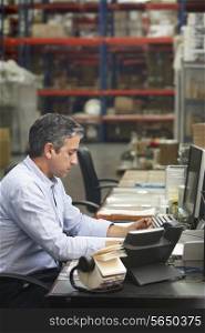 Manager Working At Desk In Warehouse