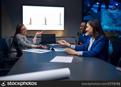 Managers on business presentation in night office. Male and female workers, dark business center interior on background, modern workplace. Managers on business presentation in night office