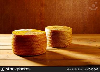 Manchego cheese from Spain in wooden table two whole pieces