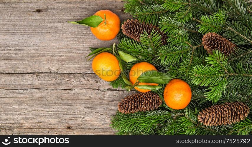 Mandarine fruits and christmas tree branches on wooden background. Christmas holidays food concept