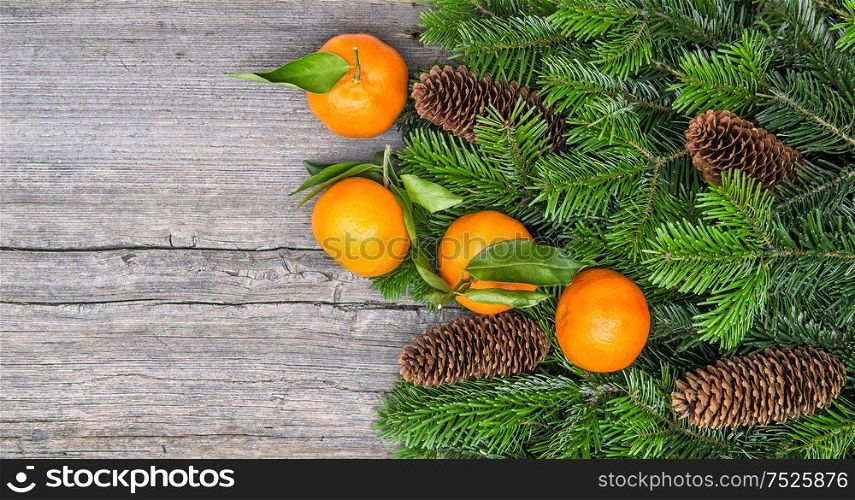 Mandarine fruits and christmas tree branches over rustic wooden background. Christmas holidays food concept