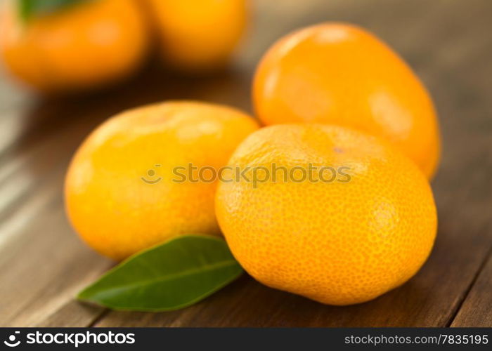 Mandarins on dark wood with leaf (Selective Focus, Focus on the front of the first mandarin)