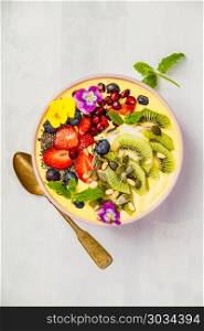 Mango banana pineapple turmeric breakfast superfoods smoothie bowl topped with fruits, berries and seeds. Overhead top view flat lay. Mango banana pineapple turmeric smoothie bowl