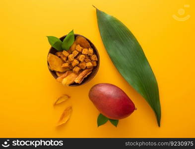Mango dried slices and balls in bowl plate on yellow background.Top view.