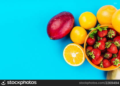 mango oranges bowl strawberries blue background