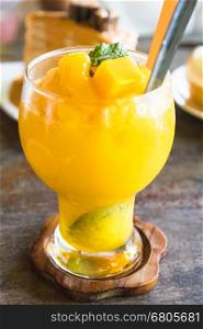mango smoothie in glass on wooden table