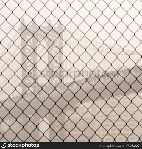 Manhattan Bridge through a chain link fence in Manhattan, New York City, U.S.A.