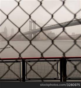 Manhattan Bridge through a chain link fence in Manhattan, New York City, U.S.A.