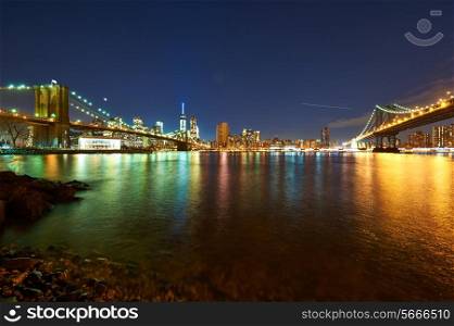 Manhattan skyline view at night from Brooklyn between Brooklyn Bridge and Manhattan Bridge in New York City
