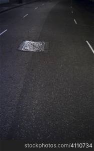 Manhole cover on tarmac, London