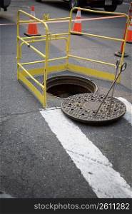 Manhole surrounded by a barricade on the road