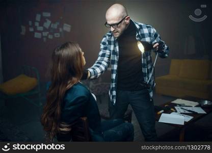 Maniac kidnapper shines a flashlight in the face of his victim. Kidnapping is a serious crime, crazy male psycho, kidnap horror, violence. Maniac shines a flashlight in face of his victim