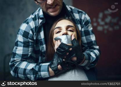 Maniac kidnapper tormenting his scared female victim. Kidnapping is a serious crime, crazy male psycho, kidnap horror, violence. Maniac kidnapper tormenting his scared victim