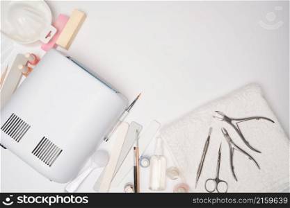 manicure and pedicure items - nail polish drying lamp, nail file, scissors and brushes over light background.. manicure and pedicure items - nail polish drying lamp, nail file, scissors and brushes over light background